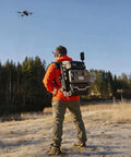 Person outdoors using Lancer300 Pro Camera Backpack With Built In 300W Power Station for on-the-go creators, drone in sky.