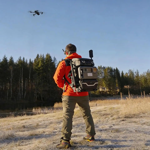 Person outdoors using Lancer300 Pro Camera Backpack With Built In 300W Power Station for on-the-go creators, drone in sky.