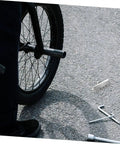 Rock Solid Rear Disc Brake Pads For Mechanical Road And Gravel Bikes Easy Swap Design Built Tough For Youth And Adult Riders Hella Durable Stopping Power Smooth Ride Seamless Installation Fits Standard Calipers For Weekend Cruises, with tools and bike wheel on pavement.