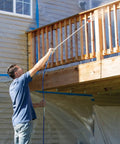Man using Heavy Duty Airless Paint Sprayer For Interior And Exterior Tasks Featuring Fully Adjustable Pressure Control to coat a wooden railing.