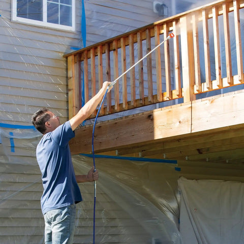 Man using Heavy Duty Airless Paint Sprayer For Interior And Exterior Tasks Featuring Fully Adjustable Pressure Control to coat a wooden railing.