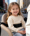 Child sitting in seat with Two-Stage Child Safety Harness For Bikes Trikes And Motorcycles Adjustable Safety Belt in an urban area