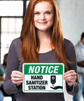 Wall Mounted Hand Sanitizer Station Sign For Offices Lobbies Or Schools Lightweight Polystyrene Frame Quick Peel Stick Mount No Hassle Setup Legit Sturdy Indoor Display held by a person indoors.