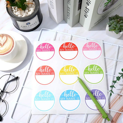 Hello My Name Is Round Name Tag Stickers Set 315 Pcs In 9 Macaron Colors on bright desk with pen and coffee.