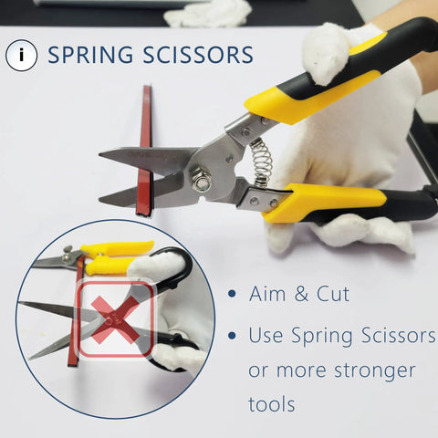 Hands using spring scissors to cut 10 Pack 36 Inch Peel And Stick Aluminum Tile Trim For Kitchen Backsplash Edge Decorative Self Adhering Matte Silver DIY Friendly No Sweat Install Durable Water And Heat Resistant Repaintable Finish.