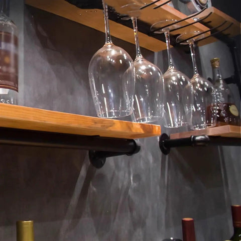 Vintage Industrial Iron Pipe Wine Rack For Badass Bar Setups And Dope Heavy Duty Countertop Organizer Wall Mounted Glass Bottle Holder displaying wine glasses on wooden shelves.