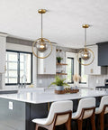 Dope Smoke Gray Glass Globe Pendant Light With Gold Rim above a modern kitchen island, large minimalist ceiling fixture.