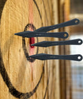 Three spikes from Six Pack 9.4 Inch No Spin Throwing Spikes Set in Durable 420HC Stainless Steel embedded in target