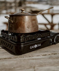 15,000 BTU Dual Fuel Portable Camping Stove For Propane Or Butane with pot outdoors on wooden table