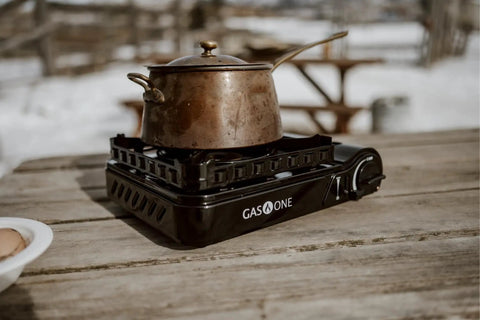 15,000 BTU Dual Fuel Portable Camping Stove For Propane Or Butane with pot outdoors on wooden table