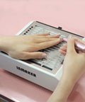 Pro Grade Nail Dust Collector Machine 60W With 2 Reusable Filters Quiet Vacuum Fan For Acrylic Nails And Poly Gel Extensions Easy To Clean Filters Low Noise Professional Salon Quality in use for acrylic nails on a salon station.