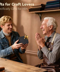A young man gives a gift to an older man in a workshop setting, surrounded by leather and fabric materials.