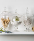 Set Of 3 Clear Glass Apothecary Jars With Lids For Candy Buffets And Home Decor Tall 10 Inch And Two 9 Inch Jars On Shelf