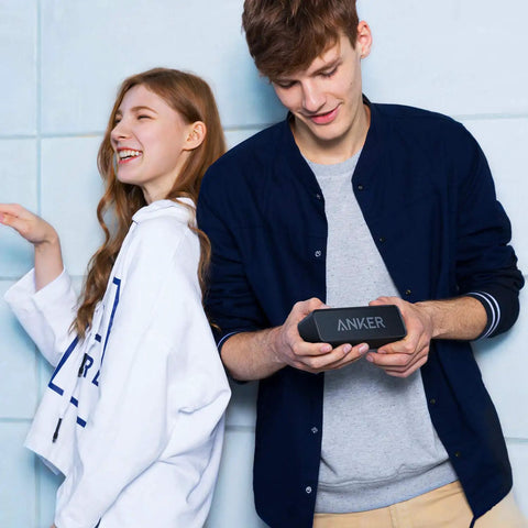 Two people enjoying music from an upgraded Bluetooth speaker with IPX5 waterproof, rich stereo sound, deep bass, and 24 hour playtime.