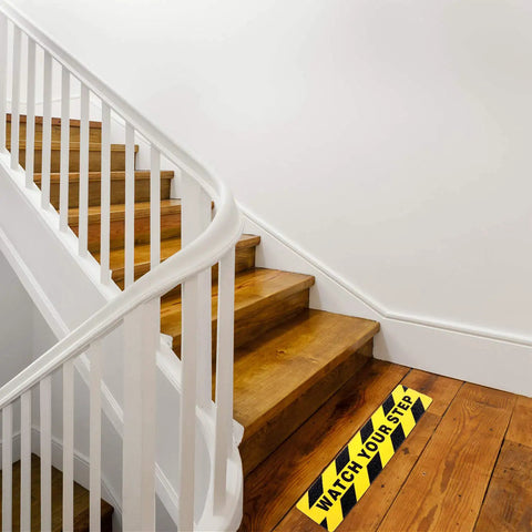 Two Pack Watch Your Step Floor Stickers Anti Slip Safety Decal 6X24 Inch on wooden stairs with yellow and black design.