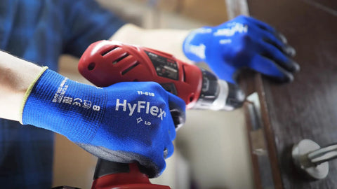 Person using drill while wearing HyFlex 11-618 Ultra Thin Nylon Safety Gloves For Automotive And Fabrication, Size 11 2XL, Blue.