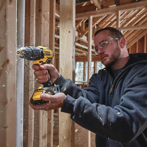 Person using Atomic 20V Max Cordless Hammer Drill With 1/2 Inch Chuck, ultra compact for tight spaces, in a wood frame building