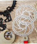 Top Notch Mechanical Disc Brake Kit For Mountain Bike With Front And Rear Rotors And Dual Knob Aluminum Calipers In Silver on wooden surface.
