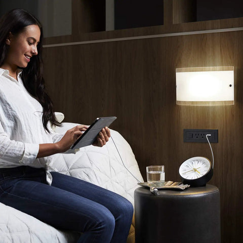 Radiant Furniture Power Center with USB and Switch Recessed Power Strip mounted on wall near bed with devices charging