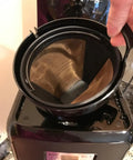 Hand holding Gold Tone Permanent Coffee Filter for 12 cup coffee makers including Krups Savoy Braun DeLonghi, placed in machine