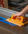 No Sweat Grip Lockdown Push Block With Retractable Holder and Traction Pad in use on a table saw with wood.