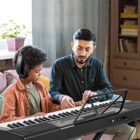 Instructor teaching child on 61 Key Learning Piano Keyboard with Lighted Keys For Beginners, Includes Stand, Pedal, Headphones and Microphone.