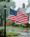 Heavy Duty 5x8 American Flag For Outdoor Use Built To Last Embroidered USA Stars And Stripes on house during rainstorm