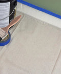 Heavy Duty Canvas Safety Drop Cloth With Slip Resistant Dots For Floors And Work Surfaces 10 Oz 4 By 15 Feet Perfect For Painting And Home Reno Projects next to paint cans and brush.