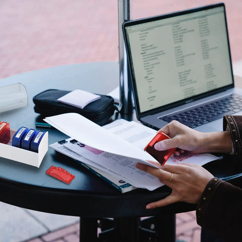 Person using Top Tier Self Inking Office Stamp Set With Eight Gotta Have Rubber Phrases Like Paid And Approved on documents.