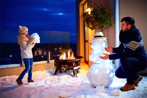 Outdoor scene with No Mess Smokeless Round Propane Fire Pit For Outdoors With Durable Weather Resistant Cover, 24-Inch Diameter, 58,000 BTU, beside snowman.