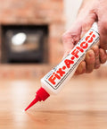Hand applying All In One Floor Repair Adhesive For Loose Hollow Tiles And Creaky Wood From A Simple Squeeze Tube With Precision Tip