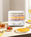 Big League Food Dehydrator Machine With Six Stackable Trays for Candy Snacks Beef Jerky Herbs on kitchen table with fruit.