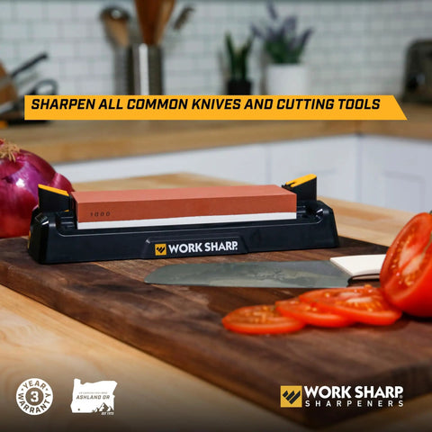 Pro Grade Kickass Benchtop Whetstone Knife Sharpener With 1000/6000 Grit Corundum Stones on a kitchen counter with knife and vegetables
