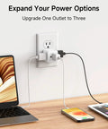 3 Pack White 90 Degree Wall Outlet Extender That Turns One Socket Into Three Extra Plugs charging devices near a laptop.