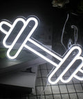 Barbell And Dumbbell Neon Sign For Home Gym Decor LED Neon Lights wall art glowing on a table, sporty vibe for fitness lovers.
