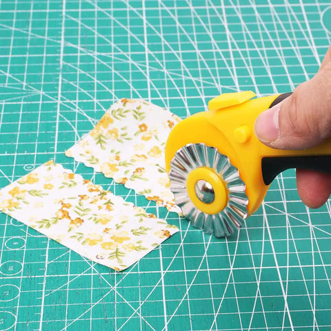 45Mm Rotary Cutter Kit With 9 Extra Blades For Fabric Quilting And Crafting, shown cutting floral fabric on a green mat
