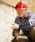 Man wearing Heavy Duty Cut Resistant Wrist Sleeves Built Tough With Reinforced Denim For Industrial Steel Handling Abrasion Proof Forearm Guards That Kick Ass At Work Sites (1 Pair) while inspecting a wall.