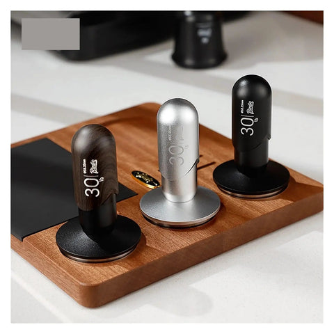 No Drama 2 In 1 Coffee Tamper And Constant Pressure Espresso Distribution Tool With Calibrated Spring For Even Powder Pressing And Flawless Puck Prep In 58mm Silver on a wooden tray with black and silver variations.