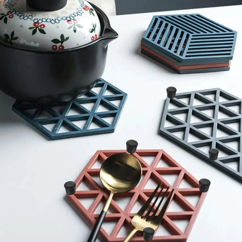 Hexagonal trivets with anti slip rubber feet for furniture 8 pack placed with kitchen utensils on a white table.