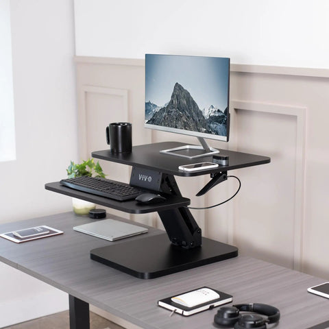 No Brainer Height Adjustable 25 Inch Standing Desk Converter with monitor and keyboard, compact black tabletop riser.