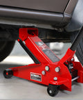 Red 3 Ton Floor Jack With Fast Lift Hydraulic Service Jack made from Heavy Duty Steel lifting a car in a garage.