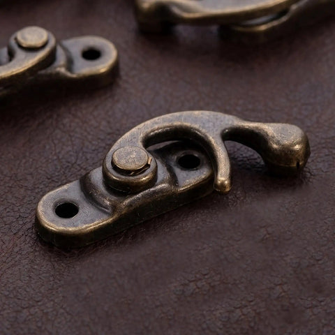 Close-up of Vintage Swing Arm Latch Set in Antique Brass with Decorative Horn Lock on leather surface