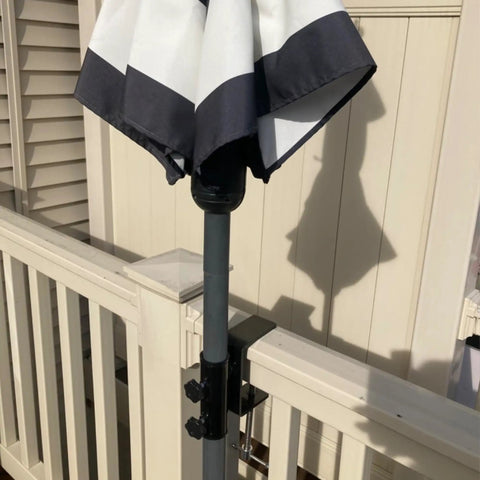 Heavy Duty Patio Umbrella Clamp Clip Steel Stand Holder Mount For Fence Posts Railings Bleachers And Tailgates Fits 1 To 1.5 Inch Poles With A 4.7 Inch Clamp Opening Stable Portable Outdoor Umbrella Support holding an umbrella on a railing