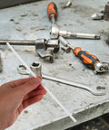 Hand holding a white PP welding rod for car bumper repair, surrounded by tools on a workbench, 20cm length.