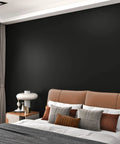 Matte Black Peel And Stick Wallpaper Roll Thick Self Adhesive Renter Friendly Wall Covering For Bedroom Living Room And Bathroom 15.8 By 394 Inches Covers 43 Square Feet Easy Install No Mess DIY Dark Wall Paper in bedroom setting with bed and nightstand.