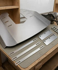 Stainless steel outboard hydrofoil plate with folded wing and mounting hardware for 40-350 HP motors on workbench