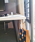 Under-desk view showing a Six Piece Crown Wall Hooks Set Zinc Alloy For Living Room, Office, And Bedroom, hanging bag and cord.