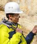 Person in safety gear holding Two Pack 28 Oz Rock Pick Hammer Set For Digging And Chipping Beefed Up Heavy Duty Forged 45 Steel Construction