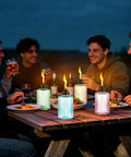 People enjoying outdoor dining with Tabletop Citronella Torches 4 Pack For Outdoor Lighting, Glass Torch Canisters With Wick And Cap, 12oz Each.