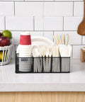 Countertop Paper Plate Organizer With 6 Compartments And Silverware Caddy, holding cups, utensils, and napkins on a kitchen counter.